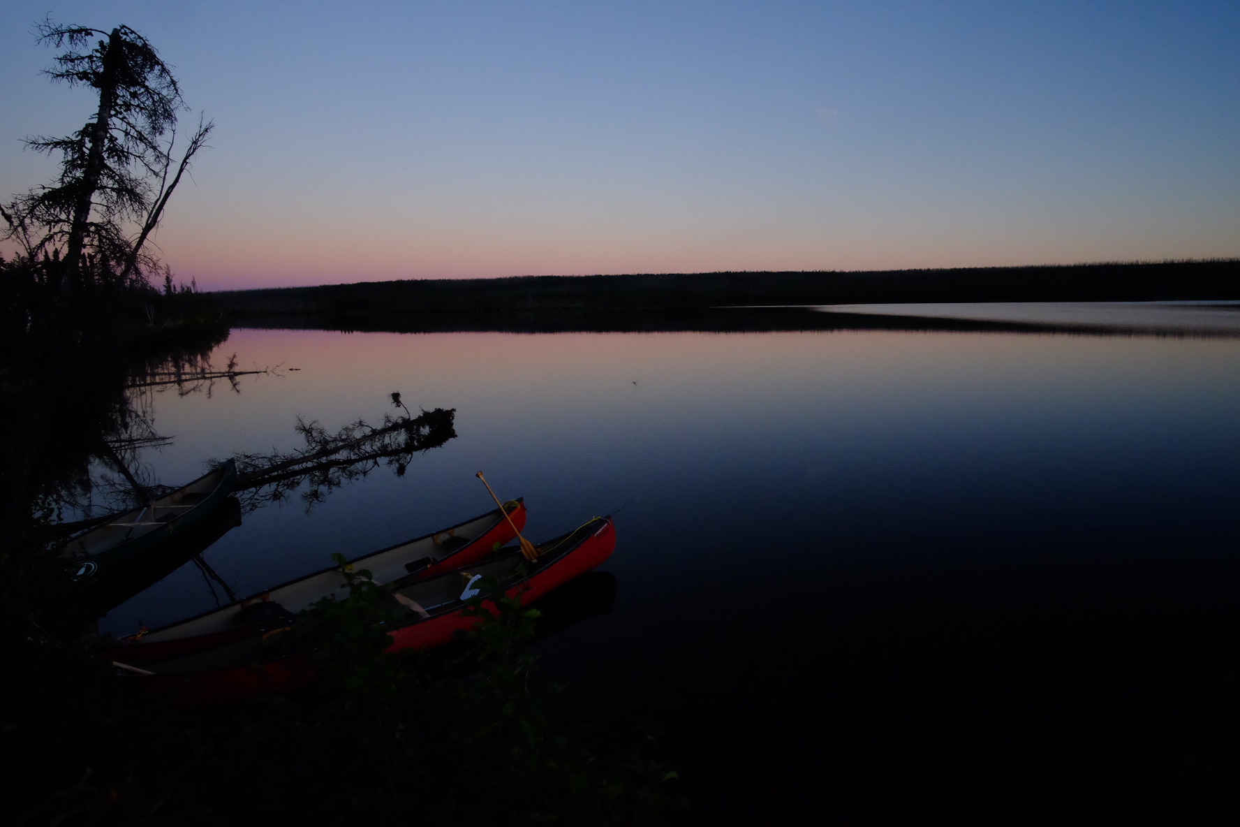 Canoes at dusk on a glassy lake